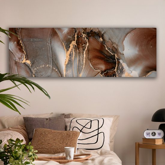 Abstract canvas met bruine, grijze en gouden marmerlook patronen, boven een bed in een slaapkamer.