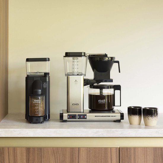 Zwarte koffiemolen en zilverkleurige Moccamaster Select koffiezetapparaat met glazen kan.