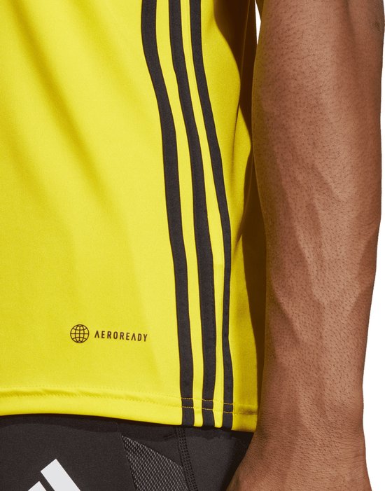 Close-up van de zijkant van een geel Adidas sportshirt met AERO READY-logo en zwarte strepen.