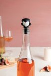 Een rosé wijnfles met vampier-wijnstopper, op een tafel met fruit en kaas.