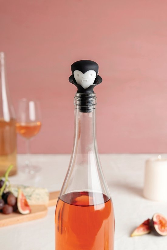 Een rosé wijnfles met vampier-wijnstopper, op een tafel met fruit en kaas.