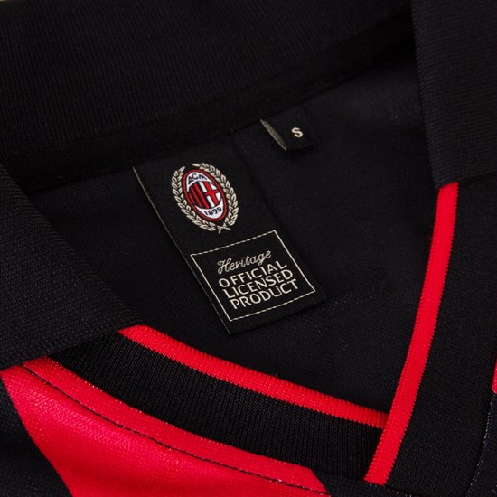Kraagdetail van een zwart voetbalshirt met rode strepen en 'Heritage Official Licensed Product' label.