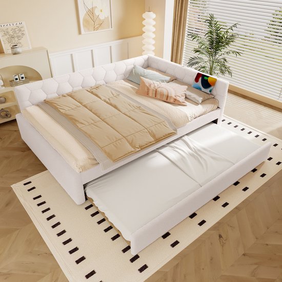 Witte slaapbank met uitschuifbaar bed, opgemaakt met dekens en kussens.