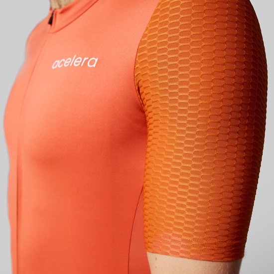Oranje wielershirt met korte mouwen, met een hexagon textuur op de mouwen en het 'acelera' logo.