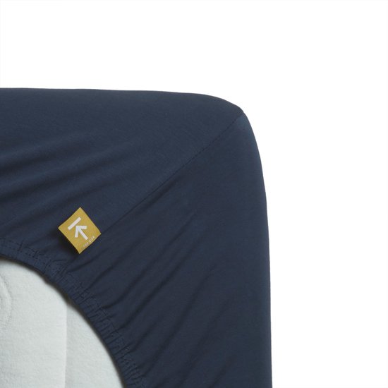 Donkerblauw jersey topper hoeslaken met geel merklabel.
