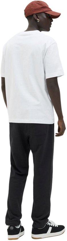 Man met witte t-shirt, zwarte joggingbroek en bruine pet, achterkant.