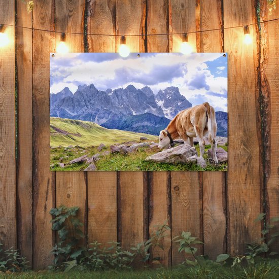 Banner met koe en bergen, opgehangen aan een houten wand.