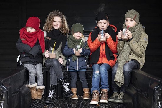 Vijf kinderen met winterkleding en mutsen, drinkend uit potjes met warme chocolademelk.