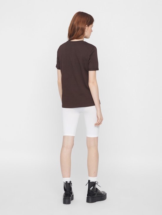 Model van achteren gezien, draagt een bruin shirt en witte biker shorts.