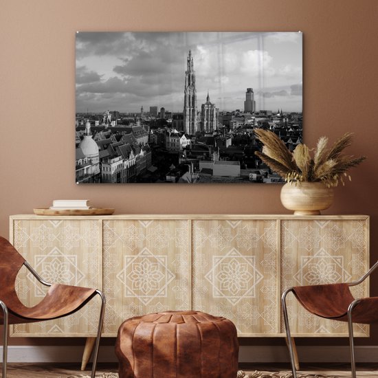 Zwart-wit stadsgezicht van Antwerpen met de kathedraal, hangend boven een dressoir met lederen stoelen.