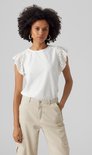 Femme portant un haut blanc court à volants et détails ajourés, et un pantalon cargo beige.