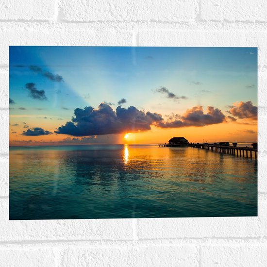 Muursticker - Zonsondergang achter Wolken bij Huisje op de Oceaan - 40x30 cm Foto op Muursticker