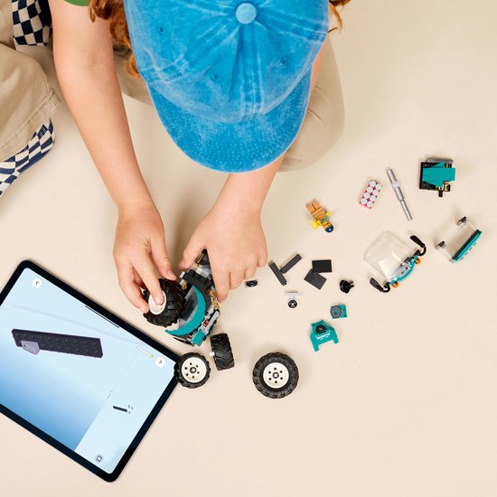 Jongen met blauwe pet bouwt met losse LEGO-onderdelen en een tablet.