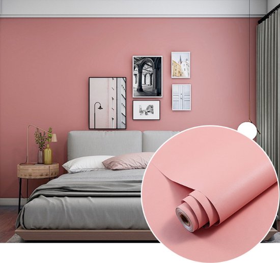 Chambre à coucher avec un mur rose, un lit avec de la literie grise et un rouleau de papier adhésif rose.