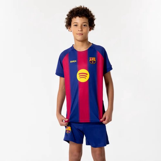 Jongen die een voetbaltenue draagt met rood-blauwe strepen, het FC Barcelona logo en Spotify logo op de voorkant.