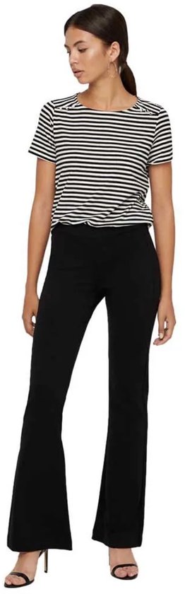 Vrouw in gestreepte top en zwarte flared broek, staand.