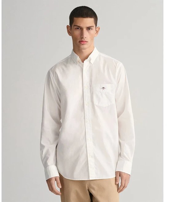 Wit Gant overhemd met geborduurd logo op borstzakje, gedragen door een man met beige broek.