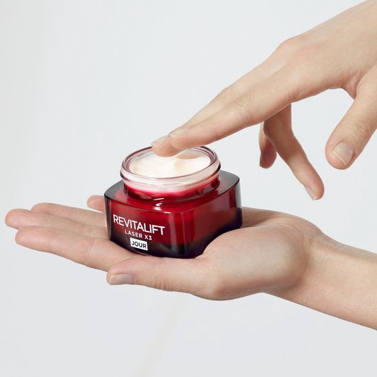Hand met vinger die crème uit rode pot Revitalift Laser X3 JOUR haalt.