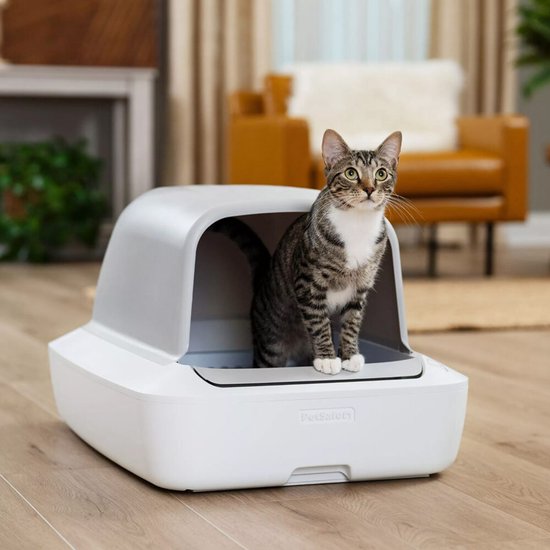 Grijze zelfreinigende kattenbak met kap, een gestreepte tabby kat staat erin.