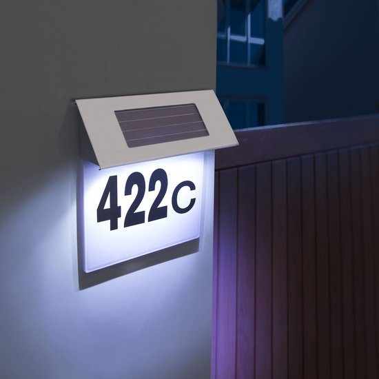 RVS solar huisnummerlamp '422c' verlicht met koel wit licht, gemonteerd aan een muur naast een hek.