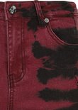 Rode denim broek met zwarte batik-achtige vlekken en een knoopsluiting met doodshoofd.