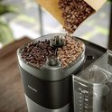 Philips koffiezetapparaat met gebogen papieren zak met koffiebonen die in reservoir vallen.