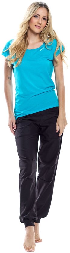 Model in een zwarte, nauwsluitende joggingbroek en een turquoise T-shirt, staand met de hand op het hoofd.