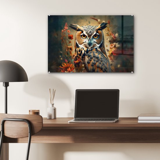 Une peinture sur verre d'un hibou aux yeux jaunes et aux plumes brunes, entouré de fleurs, accrochée au-dessus d'un bureau.