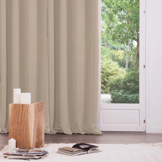 Beige verduisterend gordijn voor een raam, naast een houten bijzettafel met kaarsen.