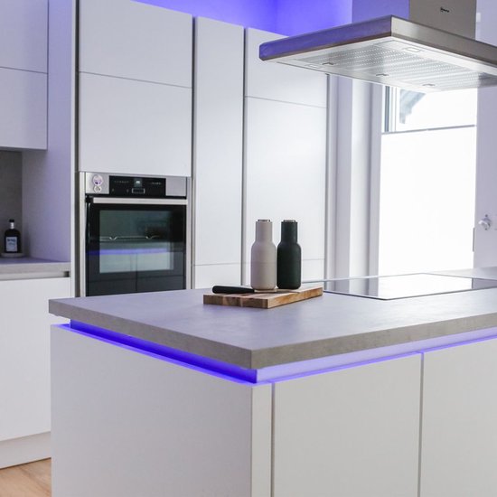 Moderne witte keuken met aanrecht, verlicht door een blauwe LED-strip.