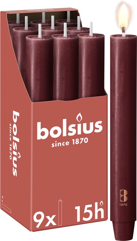 Een brandende bordeauxrode, rustieke dinerkaars van Bolsius, met een verpakking van acht andere kaarsen ernaast.