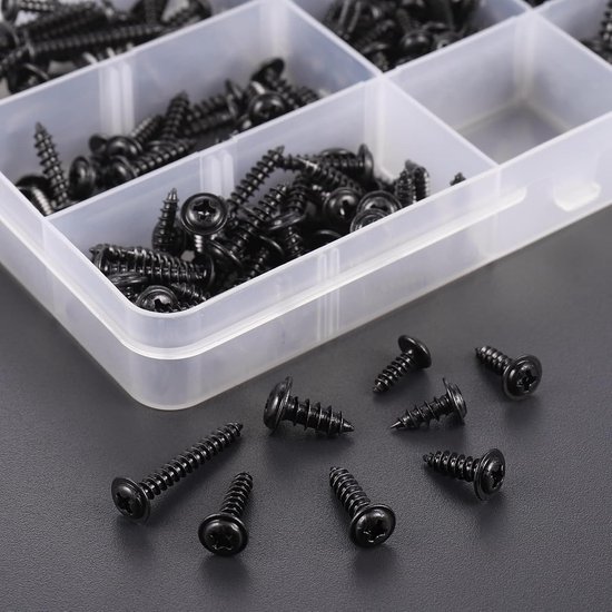 Zwarte, zelftappende schroeven met kruiskop verspreid op een grijze achtergrond, met een deel van een open assortimentsdoos.
