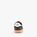 Achterkant van een zwarte Adidas sneaker met gouden accenten op de hiel en beige zool.