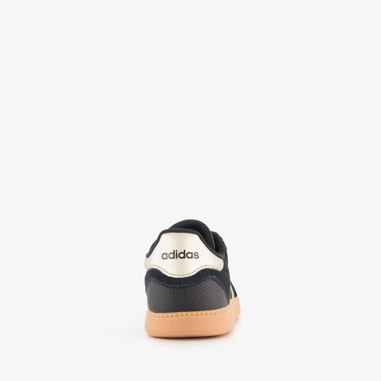 Achterkant van een zwarte Adidas sneaker met gouden accenten op de hiel en beige zool.