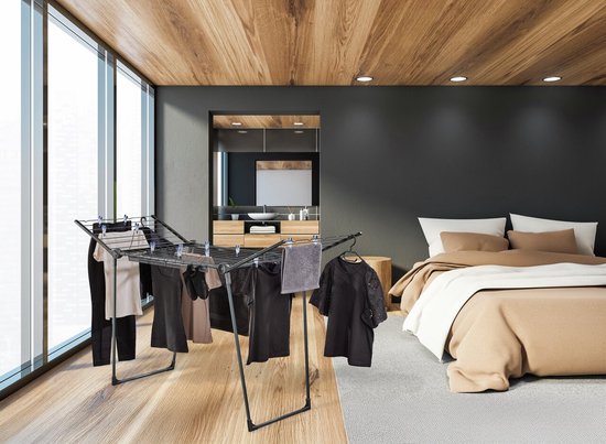Étendoir noir avec vêtements, serviette et cintres dans une chambre.