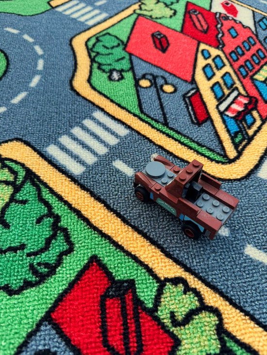 Een Lego auto op een speelkleed met een stad en wegen.