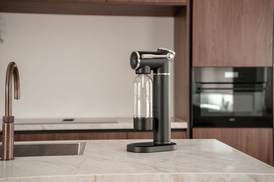 Zwarte bruiswatertoestel met doorzichtige fles in een moderne keuken.
