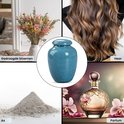 Collage met een lichtblauwe urn, gedroogde bloemen, haar, as en parfum.