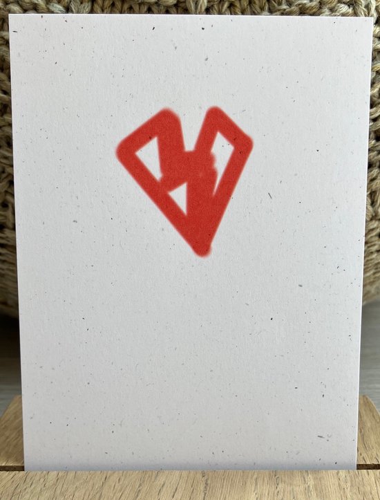 Een witte kaart met een rood, abstract hart-achtig symbool, in een houten display.