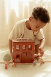 Kind speelt met de houten brandweerkazerne met 'FIRE STATION' bord en accessoires.