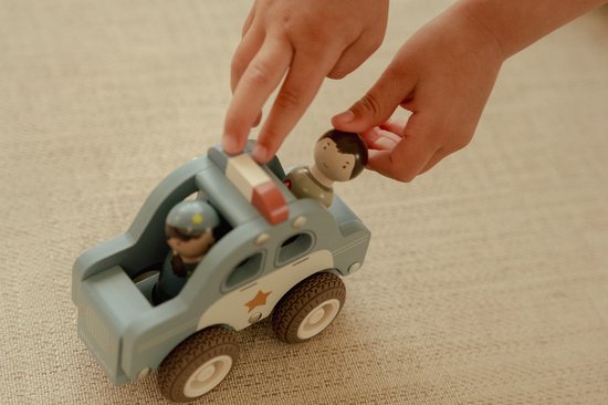 Kind speelt met blauwe houten politieauto met twee poppetjes.