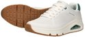 Witte Skechers sneakers met groene hiel en bruine zool, één schoen ligt op de zool.