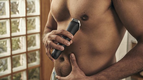 Man gebruikt zwarte Philips trimmer om borsthaar te trimmen.