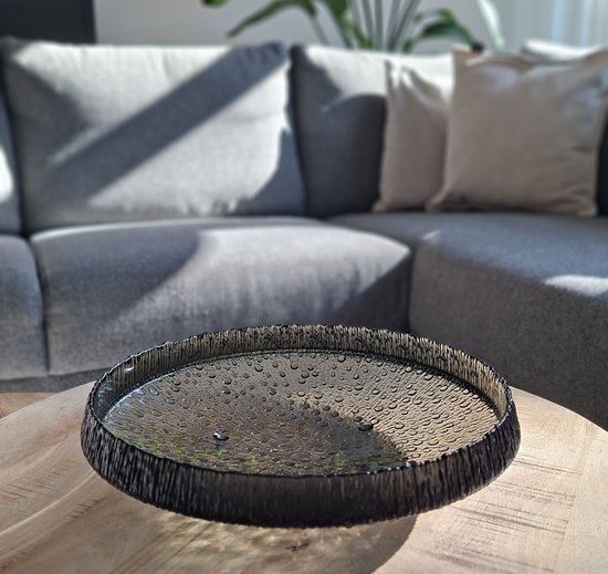 Zwarte glazen schaal met bubbels en een ruwe rand op een houten tafel.
