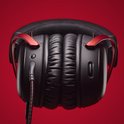 Zwarte gaming headset met rode accenten, close-up van oorschelpen en bediening.