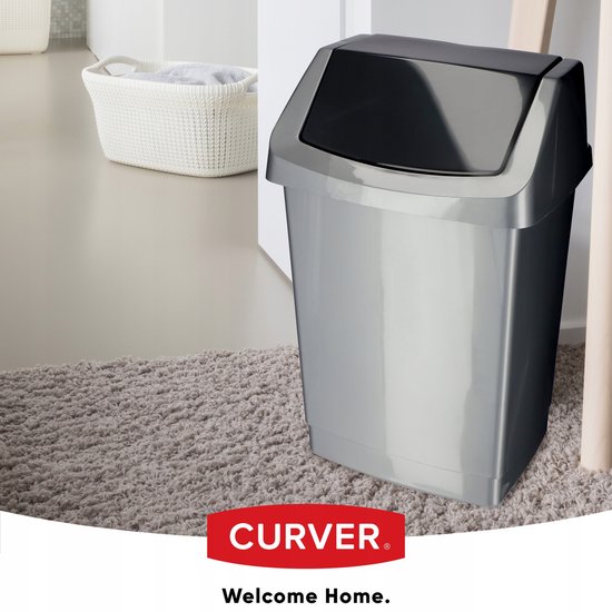 Poubelle Curver argentée avec couvercle gris sur un tapis, à côté d'une table d'appoint.