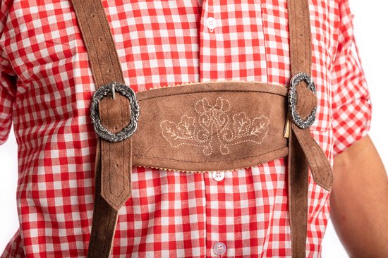 Close-up van een bruine lederhosen met decoratieve, geborduurde patronen en zilverkleurige gespen op een rood-wit geruite blouse.