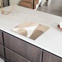 Abstracte beige beschermhoes voor inductiekookplaat op een wit marmeren aanrecht.