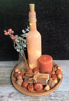 Ronde mango houten schaal - terracotta kleurige mat glazen fles met verlichting - glazen flesje met o.a. eucalyptustakje - stompkaars - gedroogde zonnebloem stelen en natuurlijk decoratie.