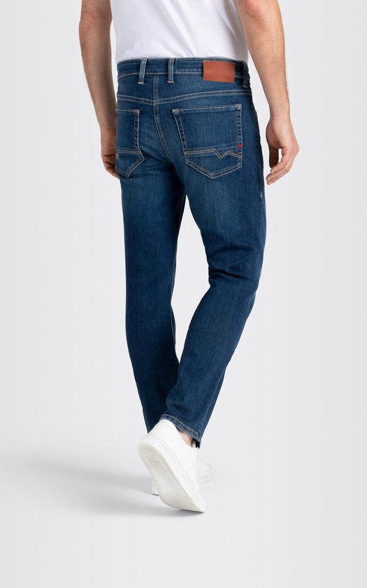 Achterkant van een man in een donkerblauwe spijkerbroek, met witte schoenen.